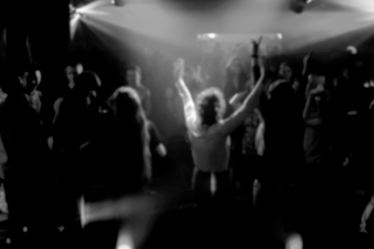 verschwommenes, schwarz-weißes Bild von feiernden Menschen in einem Club