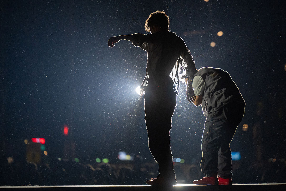 2 Künstler von hinten im Gegenlicht auf der Bühne