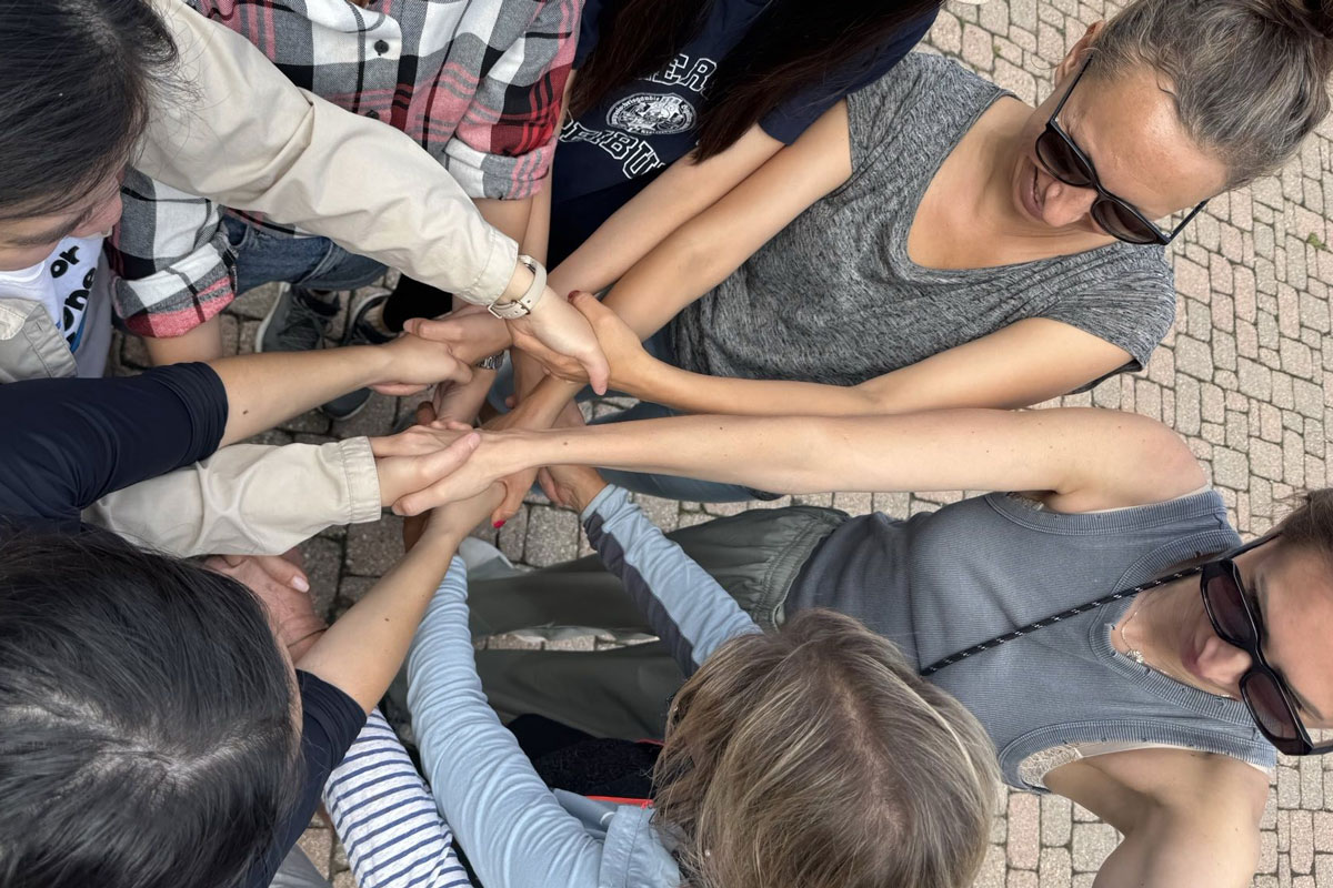 Mehrere Frauen stehen im Kreis und geben sich die Hände