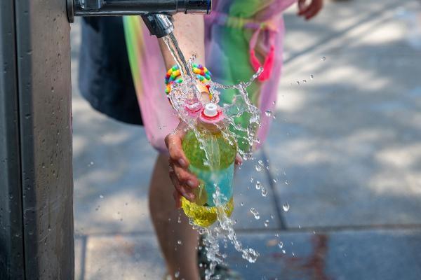 Person hält Flasche unter Wasserstele