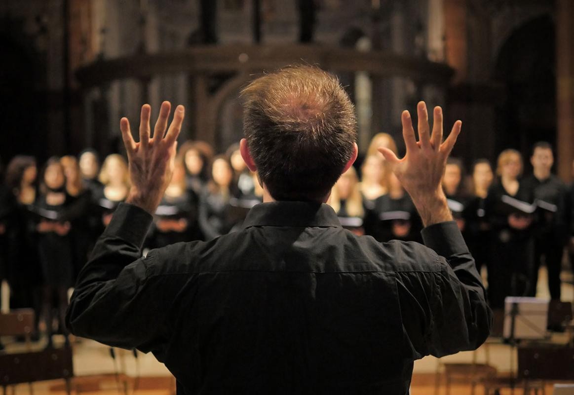 Dirigent von hinten vor Chor im Hintergrund