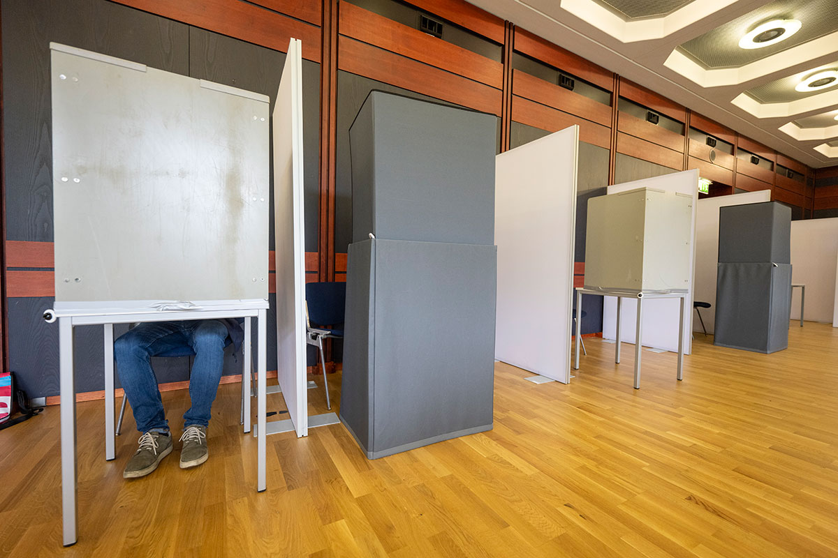 Wahllokal mit mehreren Wahlkabinen, eine davon besetzt