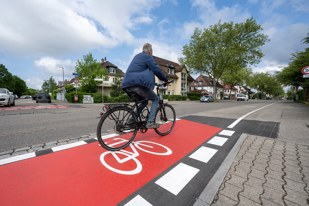 Mann auf Fahrrad fährt auf einem rot markierten Radweg