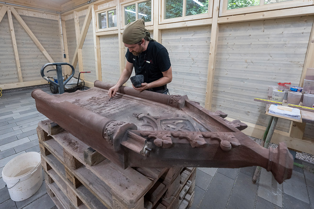 Mann arbeitet an historischem Grabstein in Halle