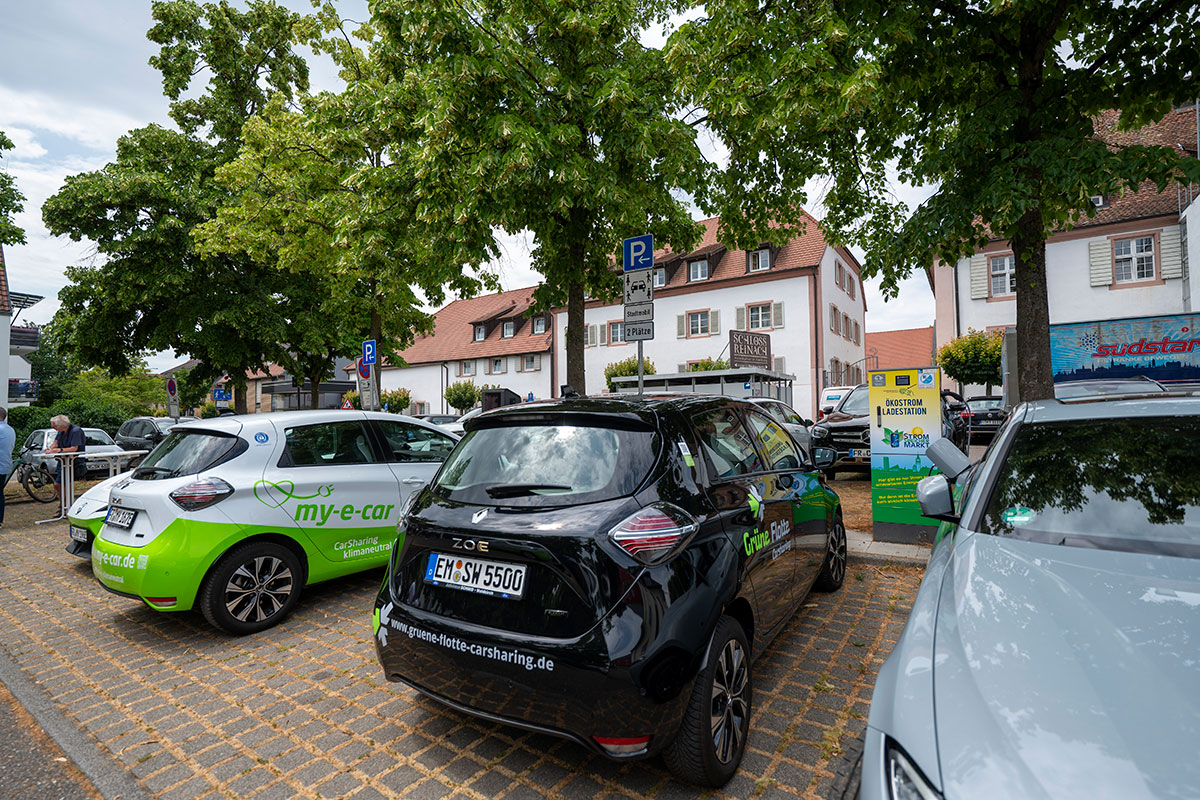 Drei Carsharing-Autos von verschiedenen Anbietern auf einem Parkplatz.