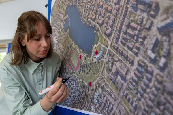 Eine Frau markiert eine Landkarte mit roten Punkten