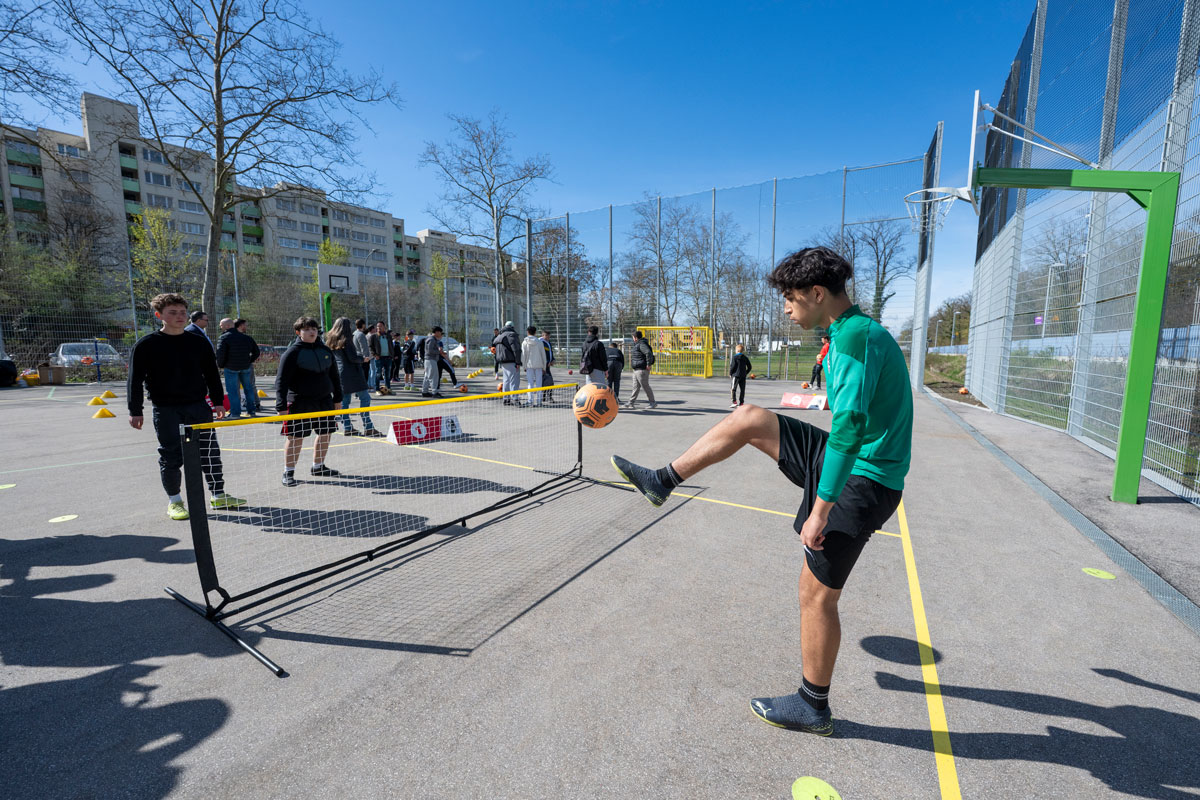 Mehrere Menschen spielen Fußball auf einem Bolzplatz