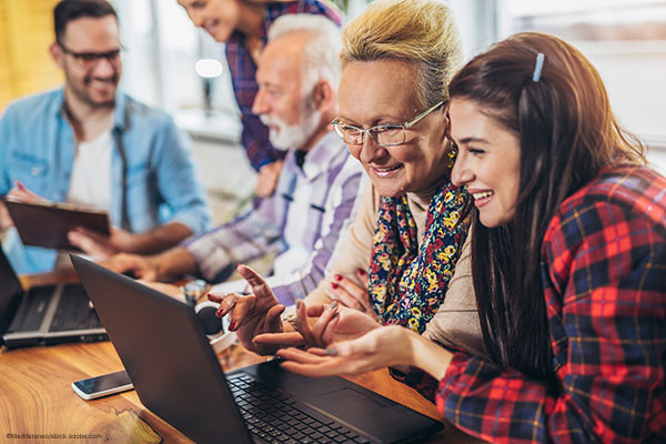 Junge und ältere Menschen an Laptops