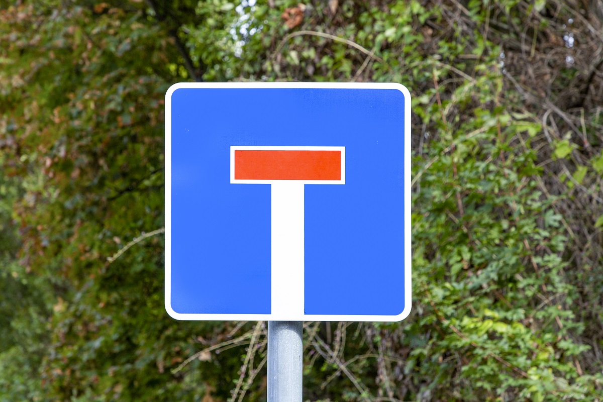 Sackgassenschild mit Sträuchern im Hintergund