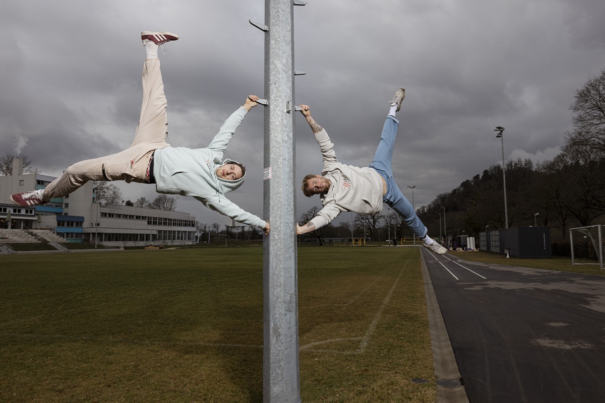 Zwei Männer hängen wie Fahnen an einer Stange im Stadion der Freiburger Turnerschaft.