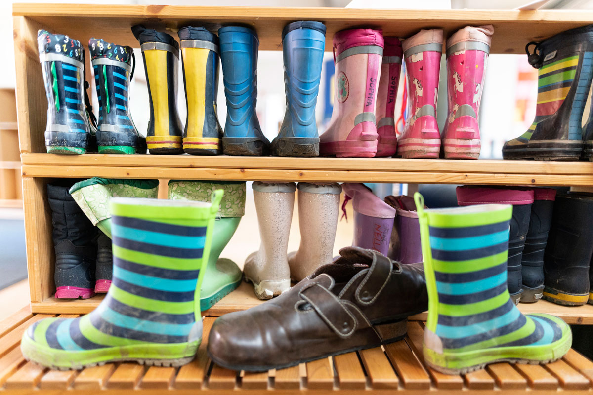 Verschiedene bunte Kindergummistiefel stehen auf einer Holzbank