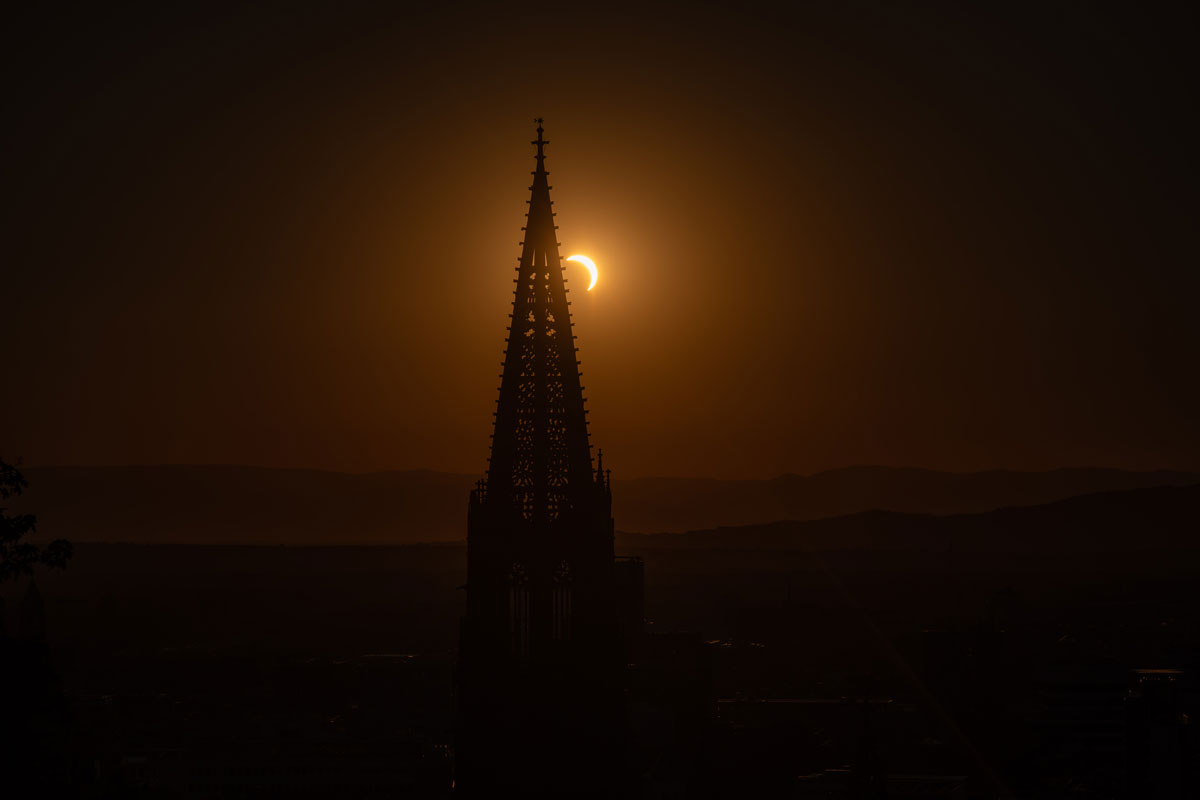 Die verdunkelte Sonnenscheibe hinter dem Münsterturm