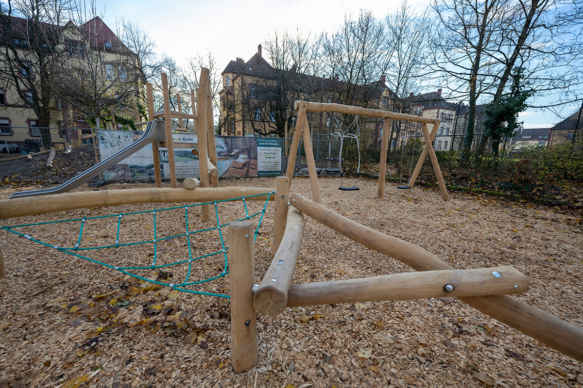 Spielplatz mit Kletternetz und Schaukel im Hintergrund