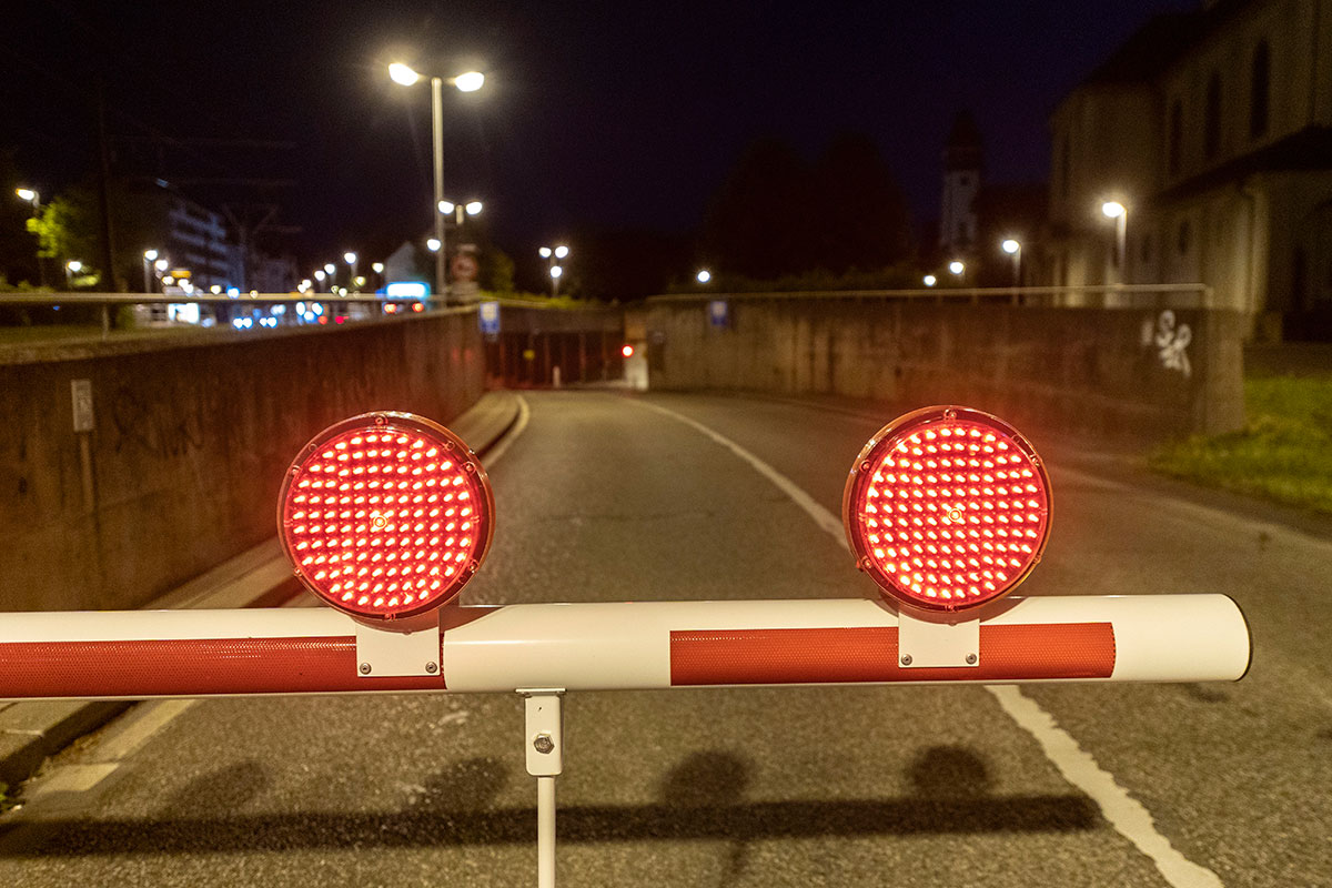 Schranke mit zwei roten Warnlichtern, im Hintergrund Einfahrt in den Tunnel