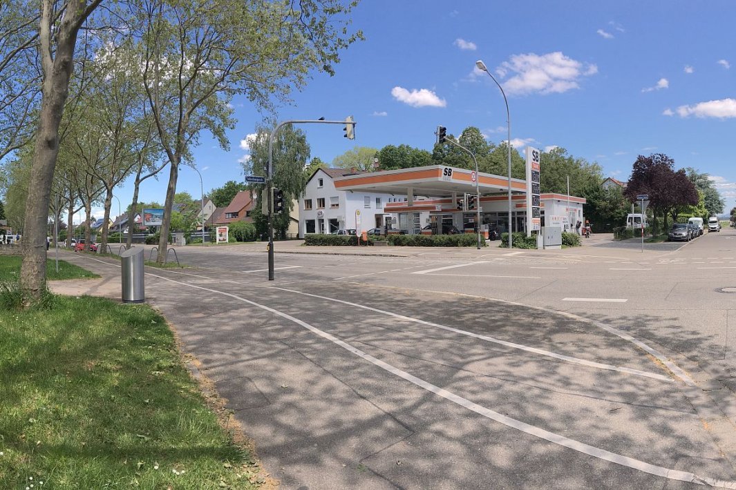 Straßenkreuzung, grüner Randstreifen, Tankstelle und Wohnhaus