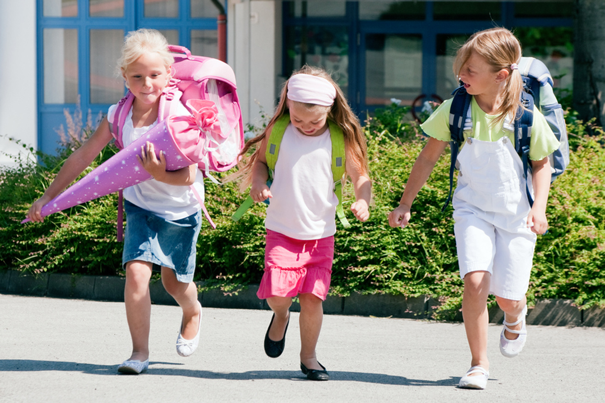 Drei Schulkinder - ein Kind hat eine Schultüte in der Hand