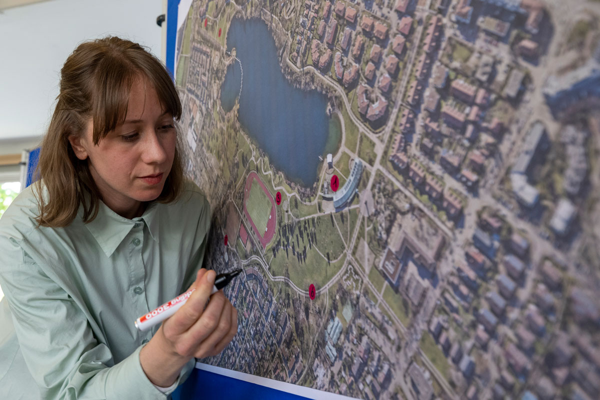 Eine Frau markiert eine Landkarte mit roten Punkten
