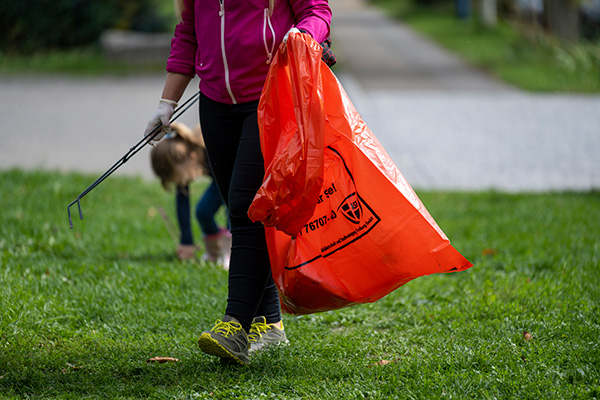 Frau mit Müllsack und Müllzange in einem Park