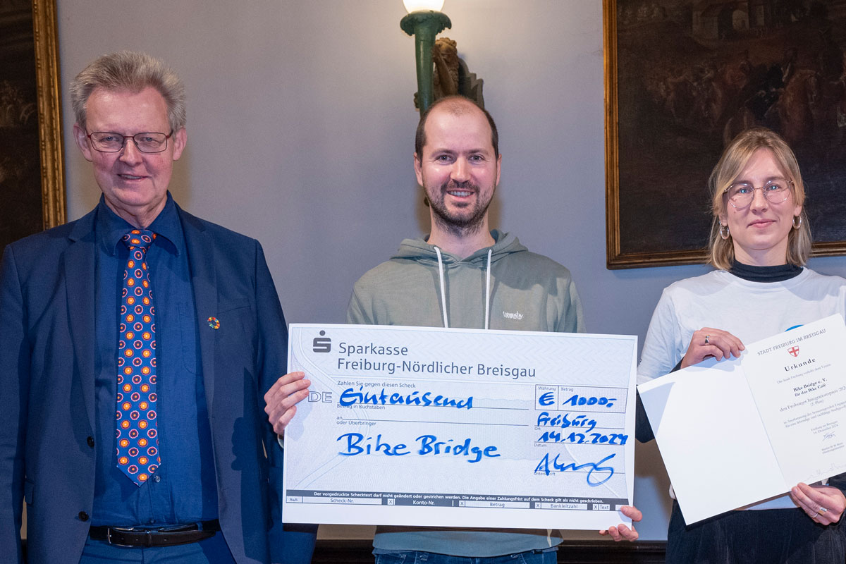 Vertreter*innen von Bike Bridge mit einem Spendencheck