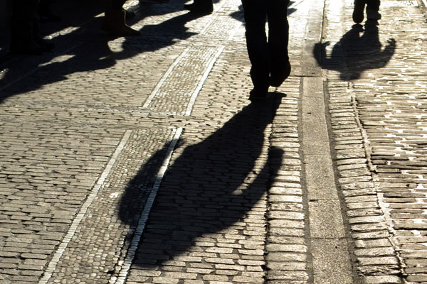 Schatten eines Passanten auf dem Gehweg