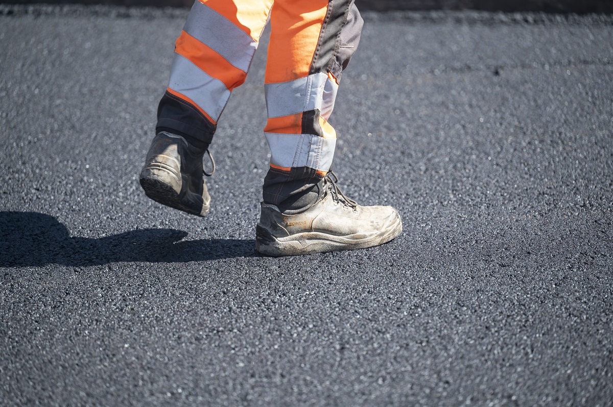 Bauarbeiter läuft über frischen Asphalt