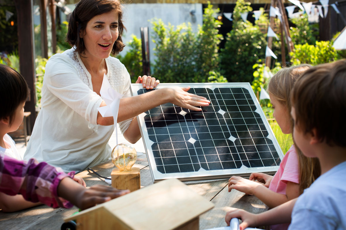 Eine Frau erklärt einer Gruppe Kinder ein Solarpaneel