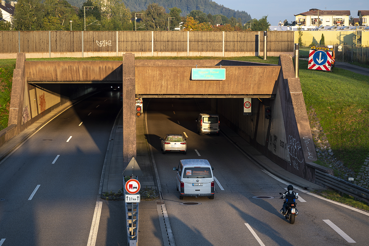 Die Ein- und Ausfahrt am Kappler Tunnel, Zwei Autos und ein Motorrad fahren gerade ein.