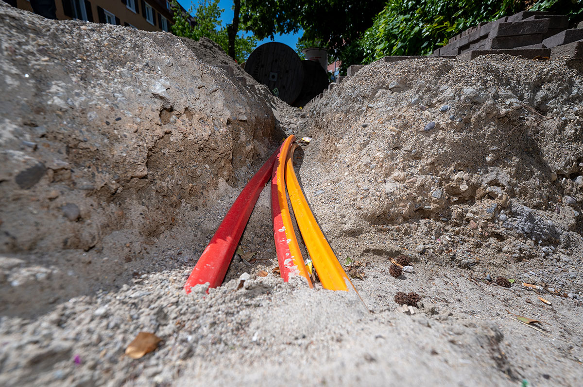 Drei rot-gelbe Breitbandkabel ragen aus der Erde