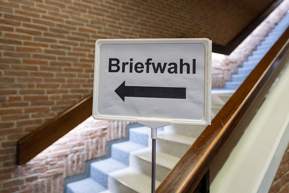 Schild mit Schriftzug "Briefwahl" und Pfeil vor einer Treppe