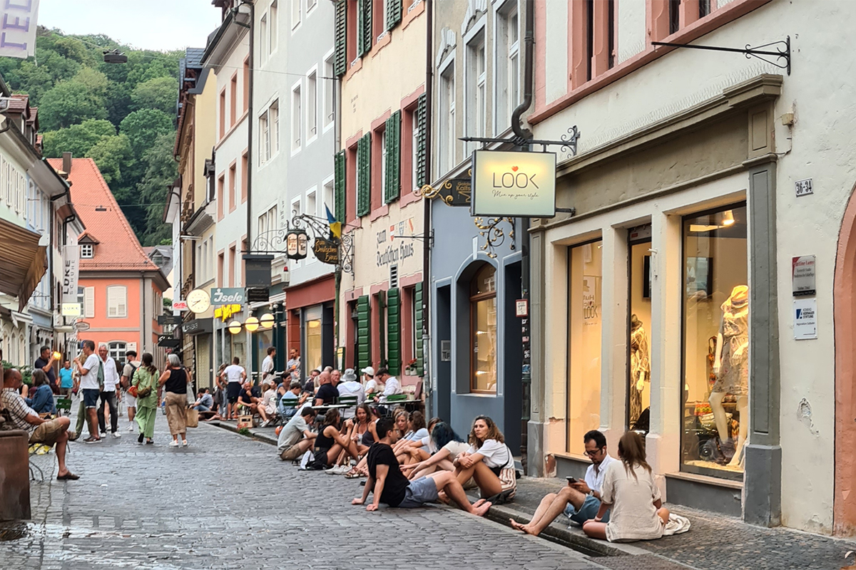 Menschen sitzen im Bächle in der Schusterstraße