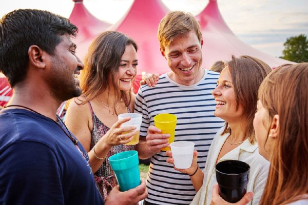 Mehrere Menschen stehen im Kreis und halten einen Becher