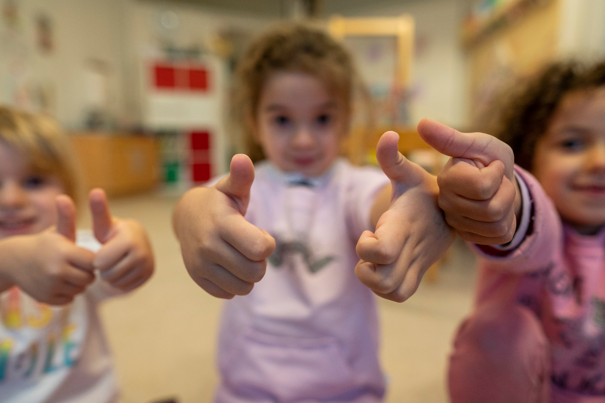 Drei Kinder zeigen "Daumen hoch" in die Kamera