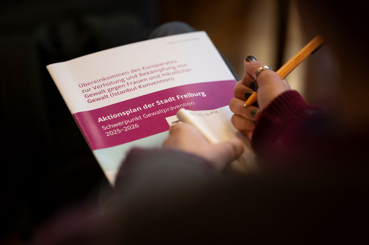 Eine Person hält den Aktionsplan Gewaltschutz und macht sich Notizen