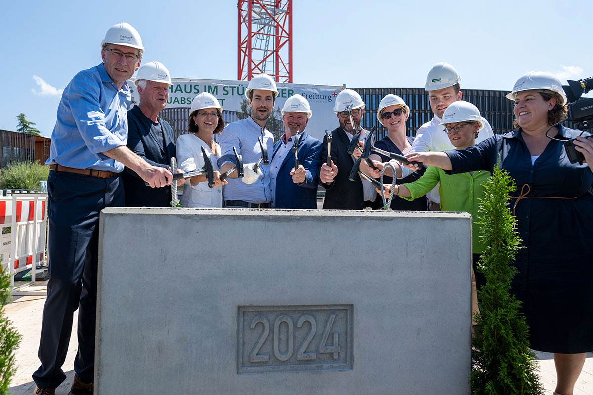 Gemeinsam mit Architekt und Generalunternehmen legen Stadtspitze und städtische Verantwortliche letzte Hand an denrun 2,5 Tonnen schweren Grundstein.