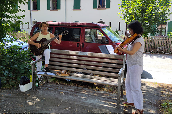 Gitarrenspielerin und Geigespielerin vor Bank