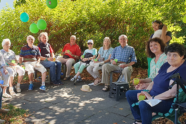 Sitzende Menschen vor Grün mit Luftballons